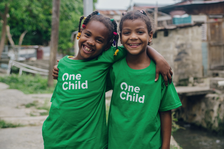 two young girls of color pose for a photo side hugging outside