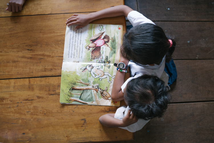 arial shot of two children reading a book sitting next to each other